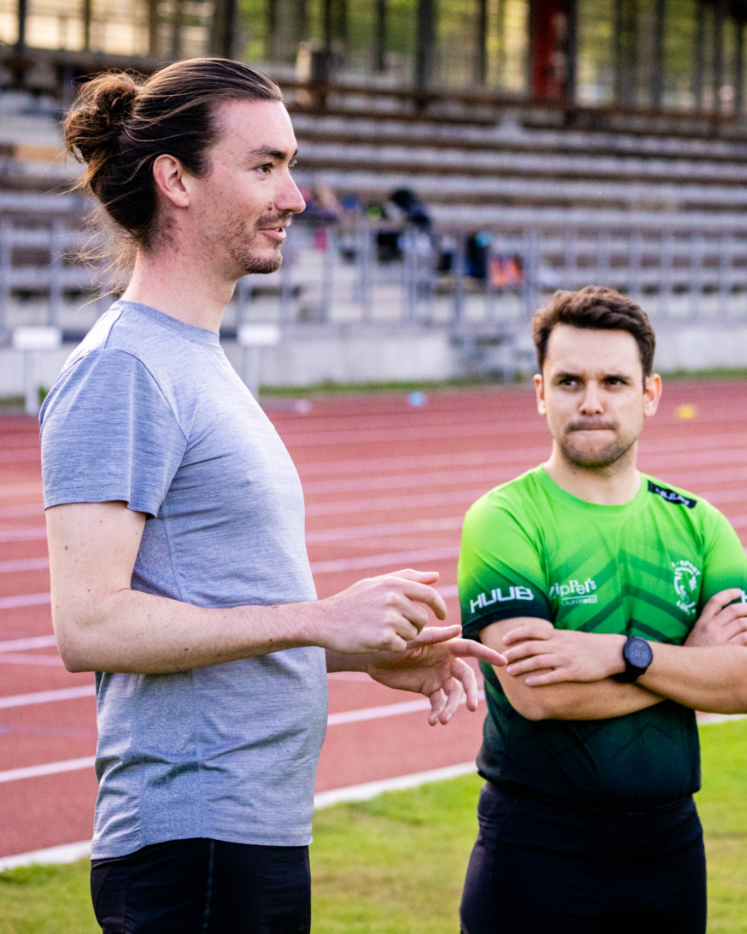 Tobias von WAAGWERKE steht auf dem Sportplatz und erklärt seinen Athleten etwas zum Lauftraining und Triathlon.