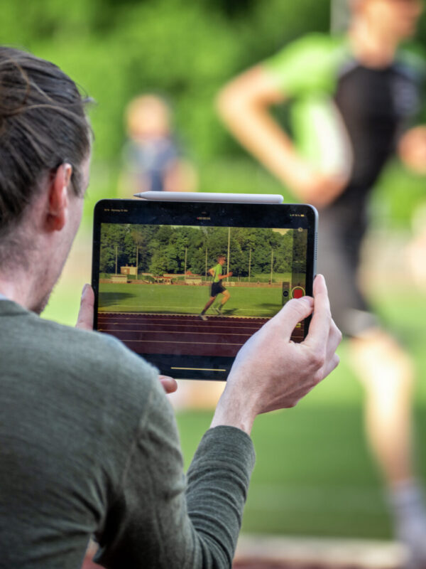 lauftraining-triathlon-coach-videoanalyse Tobias von WAAGWERKE filmt einen seiner Athleten beim Laufen, um den Laufstil zu analysieren und Potentiale in der Leistung zu erkennen.